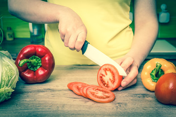 Woman cutting tomato for salad - fresh vegetables concept