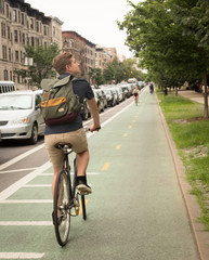 Naklejka premium Back view of modern hipster man riding bike on bike lane in the city