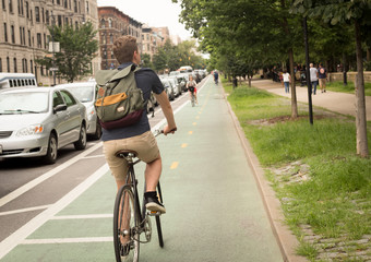 Back view of modern hipster man riding bike on bike lane in the city