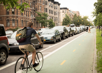 Back view of modern hipster man riding bike on bike lane in the city