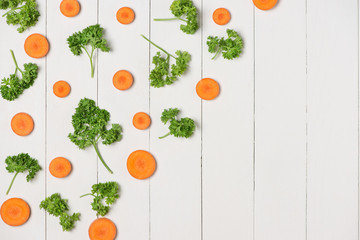 Fresh raw peeled carrot slices with vegetables on wooden table.