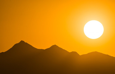 sunset over mountain silhouette in the Sonora Desert in Arizona with an intense orange and yellow sky