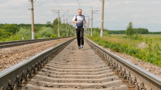 A man in sports uniforms runs on rails. He follows his health, runs cross, active life style.