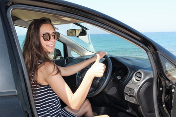 Fototapeta na wymiar A woman sitting inside a rented car with a sea view
