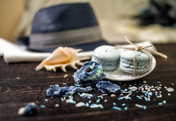 Blue and sea blue macaroons in a marine theme on a dark background decorated with rope and sea salt. White plate and light/