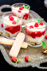 Tiramisu with raspberry in glasses on metal tray. Three portion. Italian dessert.