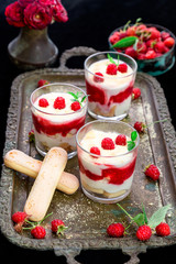 Tiramisu with raspberry in glasses on metal tray. Three portion. Italian dessert.