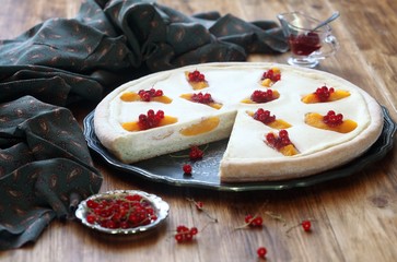 Open Cheese Pie with Peaches and Red Currants, on wooden table.