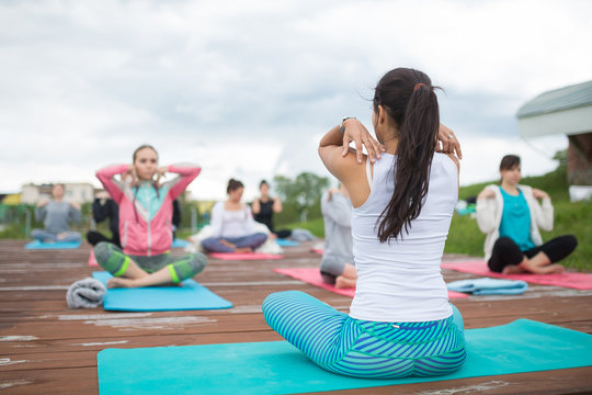 Group of people of different age yoga exercise in the park at summer. Big group of adults woman doing yoga class outdoor in nature