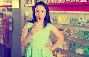 Smiling girl sucking   lollypop in  store