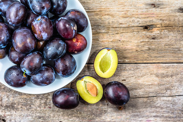 Purple plums on wooden table, autumn seasonal fruits harvest