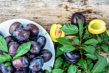 Autumnal plums on wooden table, autumn seasonal fruits harvest