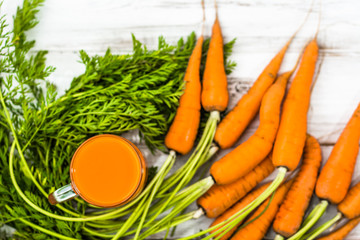 Carrot smoothie in glass and fresh carrots on wooden background