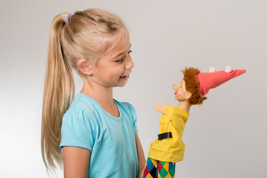 junges M&auml;dchen lacht vertieft im Spiel mit Kasper Puppe