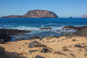 Colorful sandy seacoast of Graciosa volcanic island with black lumps of lava, Lanzarote, Canary Islands, Spain