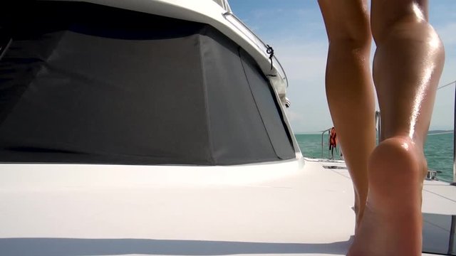 A girl with long legs walks along the deck of the yacht in slow motion. Sea view