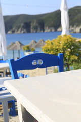 White wooden picnic table by the sea in Greece, Empty picnic table for product display, Defocused beach in the background