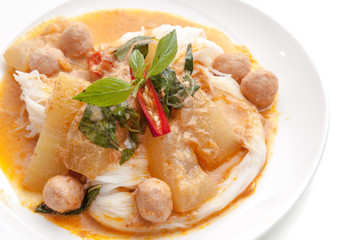 Thai style pork ball and vegetable curry served with rice noodle on white plate