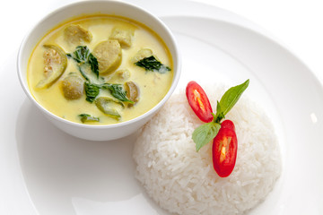 Thai style pork ball and vegetable green curry served with rice on white plate