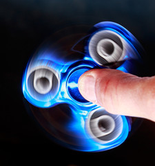 Toy spinner rotates quickly against a dark background.