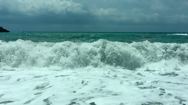 Boiling sea. Giant waves roll to the shore. Sea surf huge waves with white foam splashing around shore.