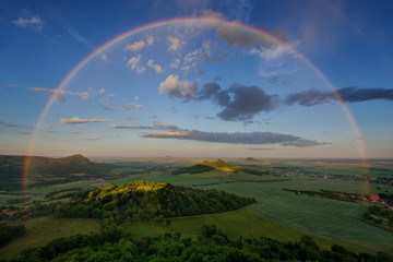 Fototapeta premium Summer rainbow over Czech Bohemian Highlands hills, Czech republic. Rainy sunset.