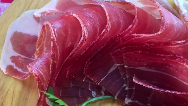 Top view of jamon slices, close up view zoom out. Prosciutto thinly sliced and served uncooked.