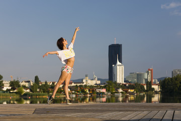 Female dancer at a river with city skyline in the back