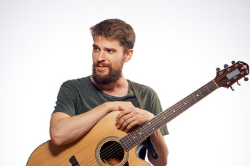 Young guy with a beard on a white isolated background holds a guitar