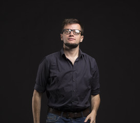 Obraz premium Young pensive man portrait of a confident businessman on a black background. Ideal for banners, registration forms, presentation, landings, presenting concept.