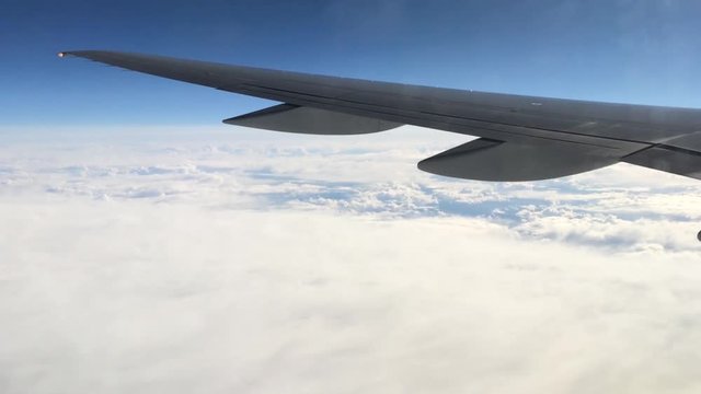 View from a plane window on the wing and the landscape below it. Wing of an airplane flying above the clouds