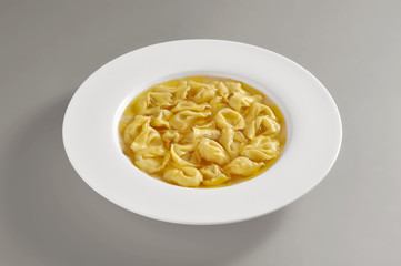 Plate with portion of tortellini pasta in broth
