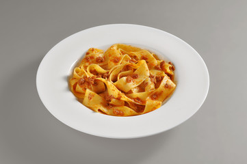 Round dish with a serving of pappardelle pasta with meat souce