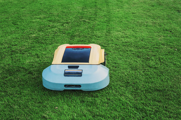 Robot lawn mower on background green grass