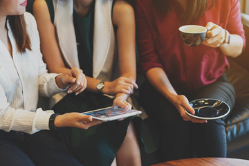 Close up scene of 3 woman using tablet together in coffee shop