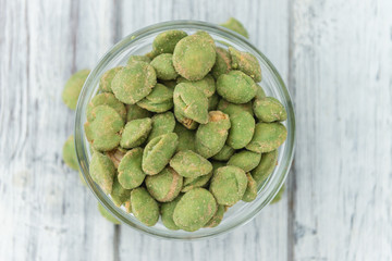 Portion of Wasabi coated Peanuts on wooden background (selective focus)