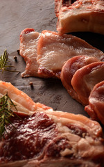 Raw meat accompanied by salt. pepper and Rosemary.