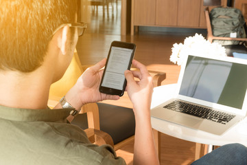 Young man use smartphone and laptop in afternoon, technology lifestyle of new generation of nomad workers