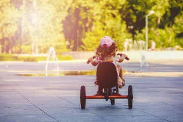 Little girl with a tricycle in the park