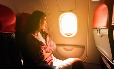 Young beautiful woman sit by window of airplane during flight