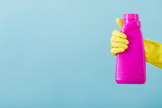 Hand in yellow glove holds a bottle of bleach on white background. cleaning