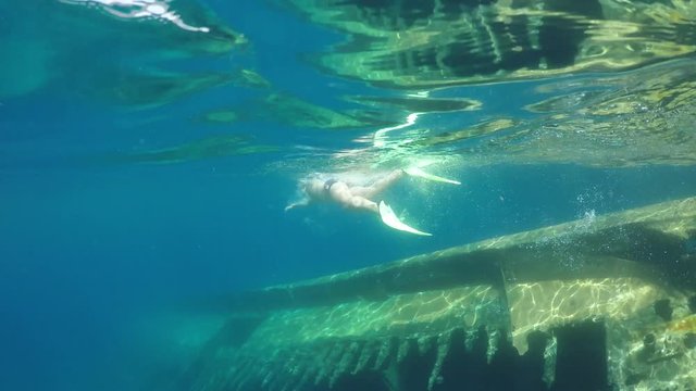 swimmer in flippers dives near sunken ship, raw, 4K
