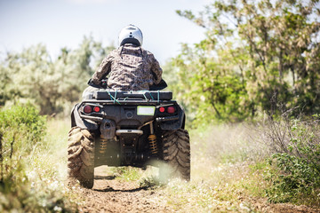 Back view of quad bike  riding along a country road. - obrazy, fototapety, plakaty