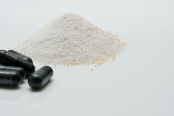 Charcoal capsules and dry powder on white background