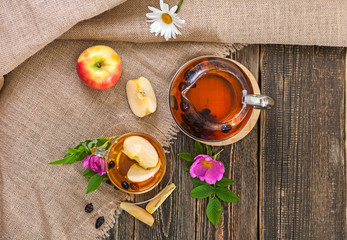 Tea with dried dog-rose and apples on a wooden table
