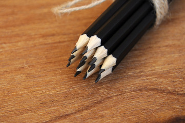 Pencils tied with a rope of straw and place in a container that is made from woven rattan.
