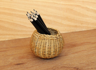 Black pencils tied with a rope of straw yarn. Against the backdrop of plywood wood pattern.