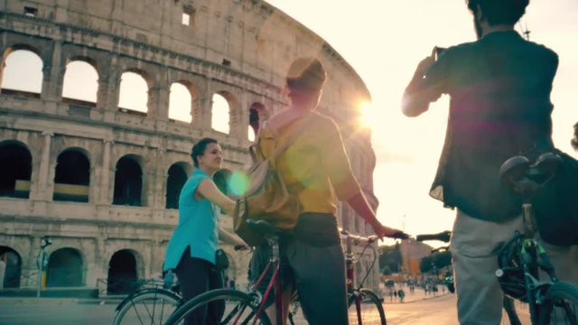 Friends riding bicycles in front of Colosseum in Rome