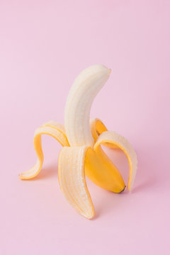 Fresh peeled banana on pink background