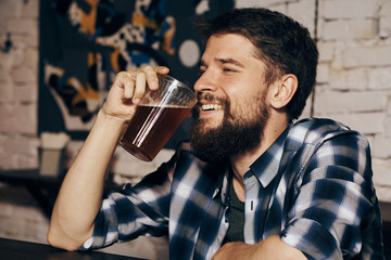 A young guy with a beard drinks beer in a bar